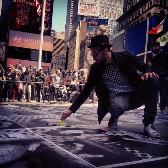 The artist himself examines portraits pasted in Times Square. Photo: Anna Verghese