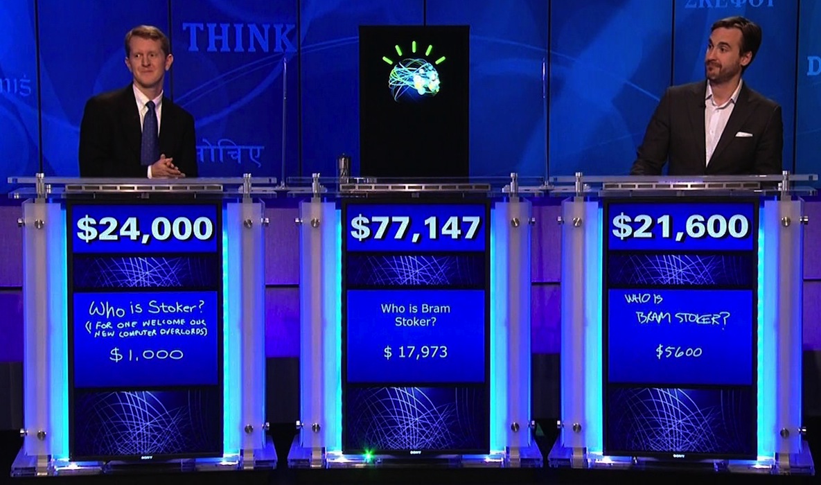 Ken Jennings (left) faces off against supercomputer Watson (center) and his fellow Jeopardy champion, Brad Rutter (right).