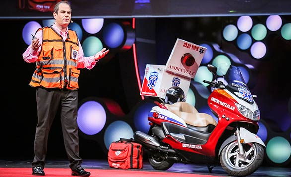 Eli Beer stands beside one of the "ambucycles" that he and other United Hatzalah EMTs ride. Photo: Courtesy of TEDMED