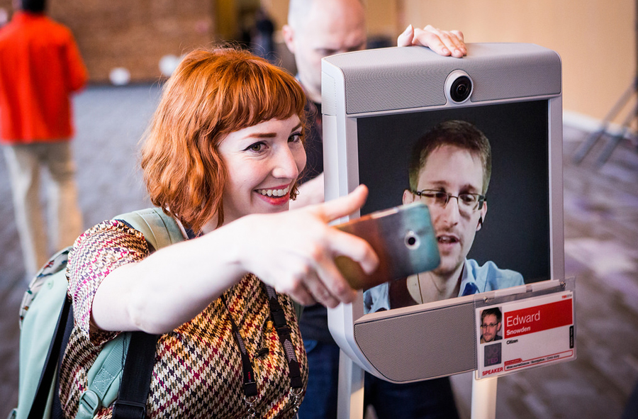 A TED attendee snaps a photo with Edward Snowden, appearing on the screen of a telepresence robot. Photo: Bret Hartman
