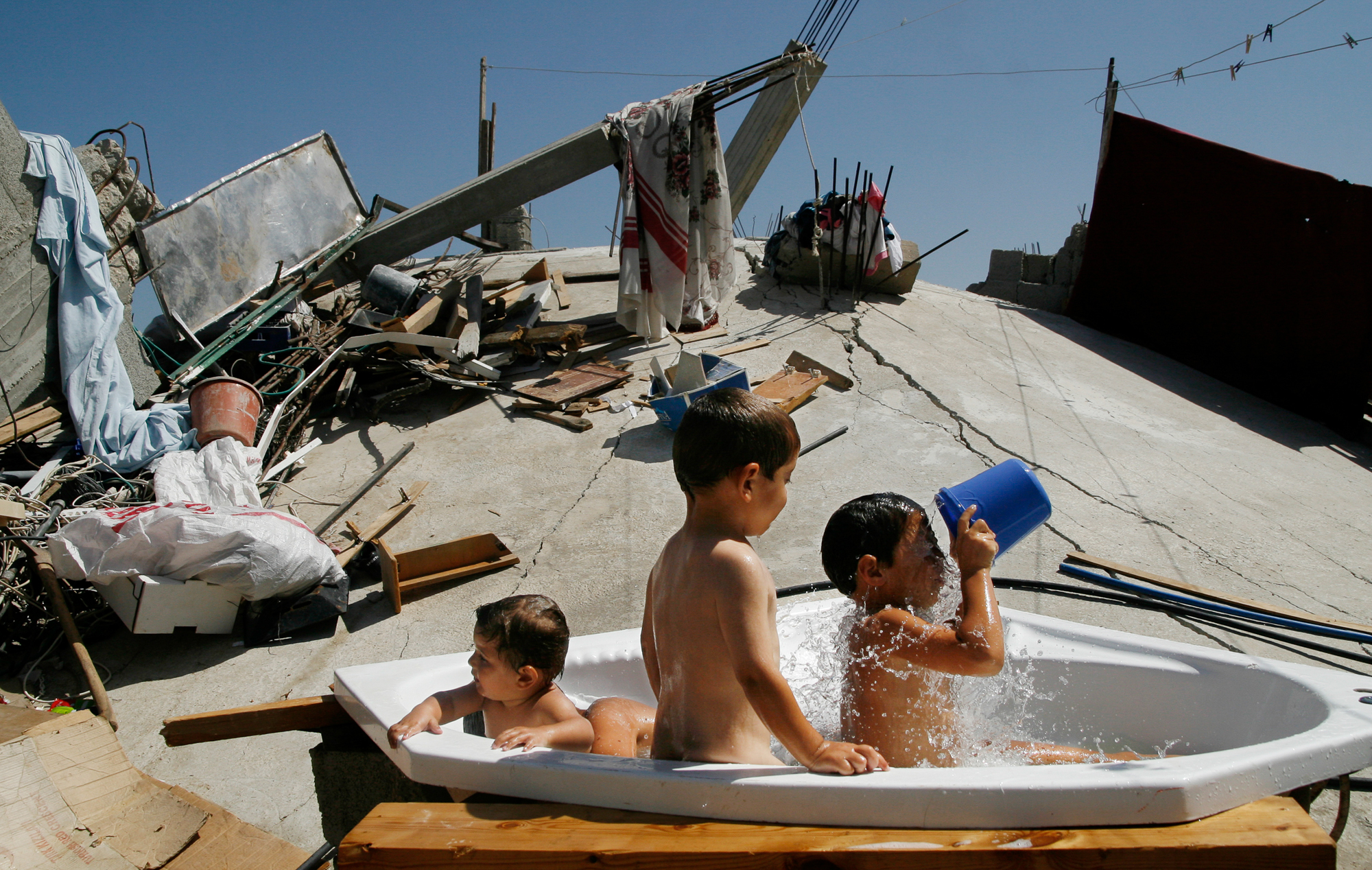 Children having a bubble bath in a Jacuzzi tub sitting atop the rubble of their house, destroyed by Israeli forces. Photo: Eman Mohammed