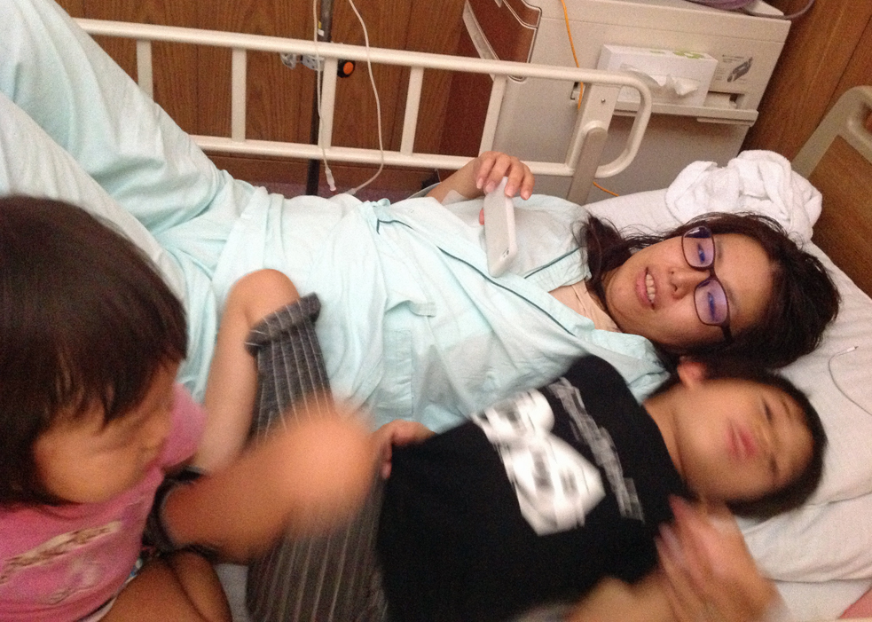 Ai Tokimatsu watches a TED Talk on her phone in the hospital, with her two children. Photo: Courtesy Ai Tokimatsu
