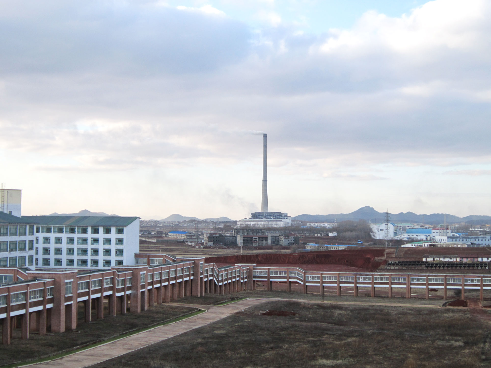 The PUST campus: the enclosed walkway connects all the buildings. The classroom building is on the left; a Pyongyang smokestack can be seen in the distance.