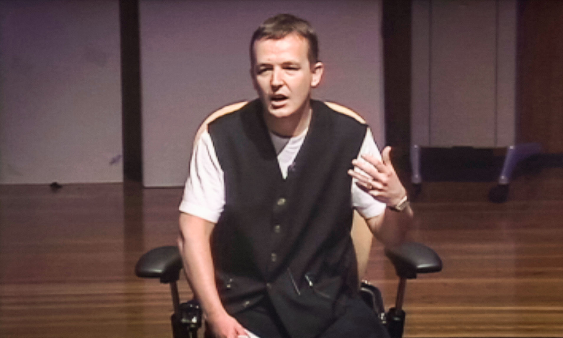 Too nervous to stand, Chris Anderson addresses the 2002 TED audience from a chair, ultimately inspiring them to follow his lead in forging TED's next chapter. Video still courtesy of TED.